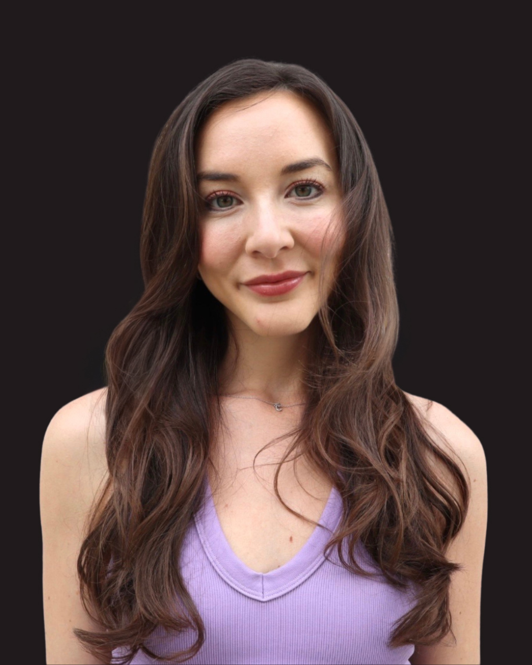 Closeup of a woman with long dark hair in front of a black background.