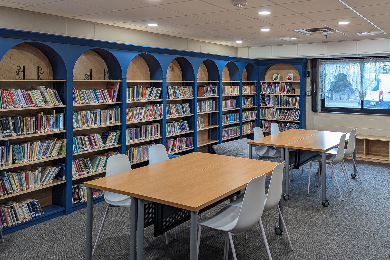 Children's library reading room with baltic birch shelving set into blue arched alcoves. Marshalltown, Iowa.