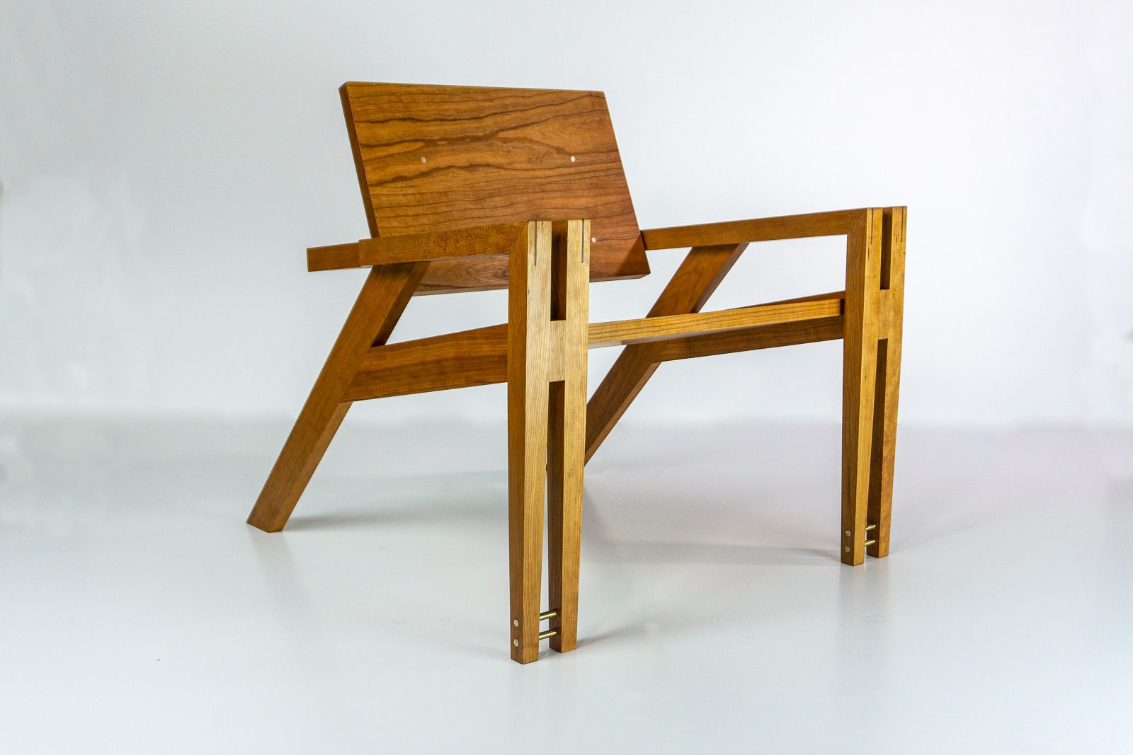 Cherry Stance lounge chair from three quarter  angle, showing the joinery and seat frame. Ames, Iowa.