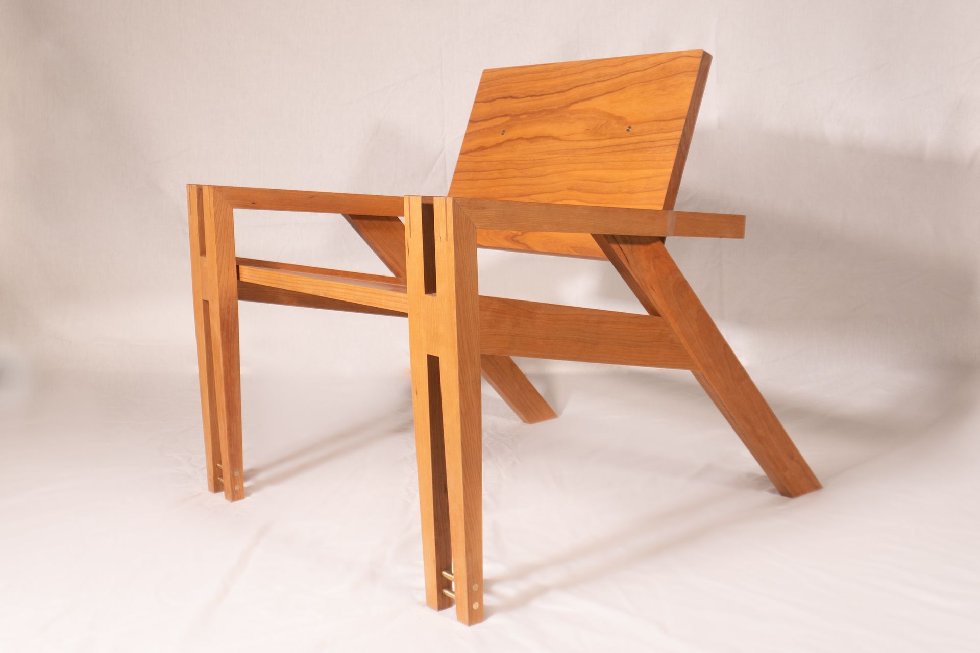 Handcrafted cherry wood lounge chair with modern geometric frame and exposed joinery, designed by Crow and Timber.