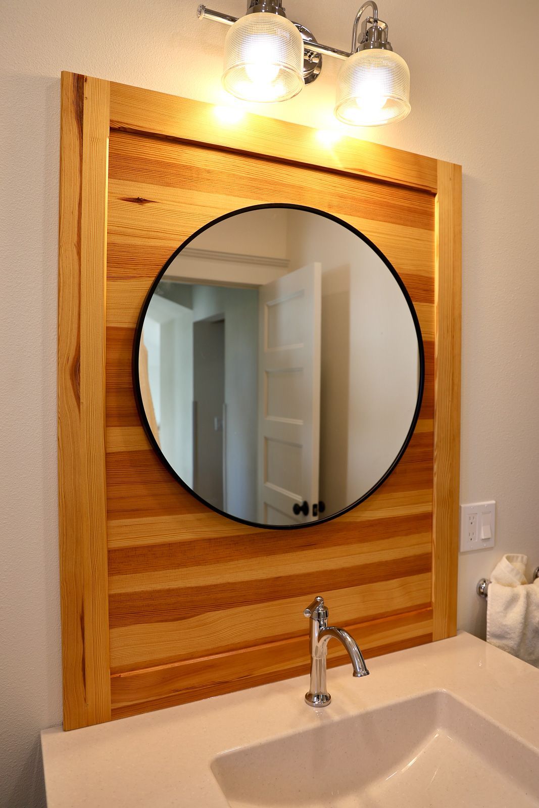 Bathroom backsplash of horizontal reclaimed Douglas fir boards framing a round mirror. Story City, Iowa.