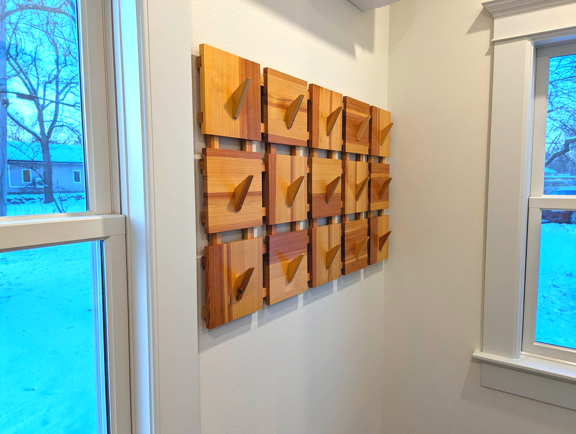 Wall-mounted coat rack made from reclaimed wood square panels and integrated angled hooks, handcrafted by Crow and Timber.