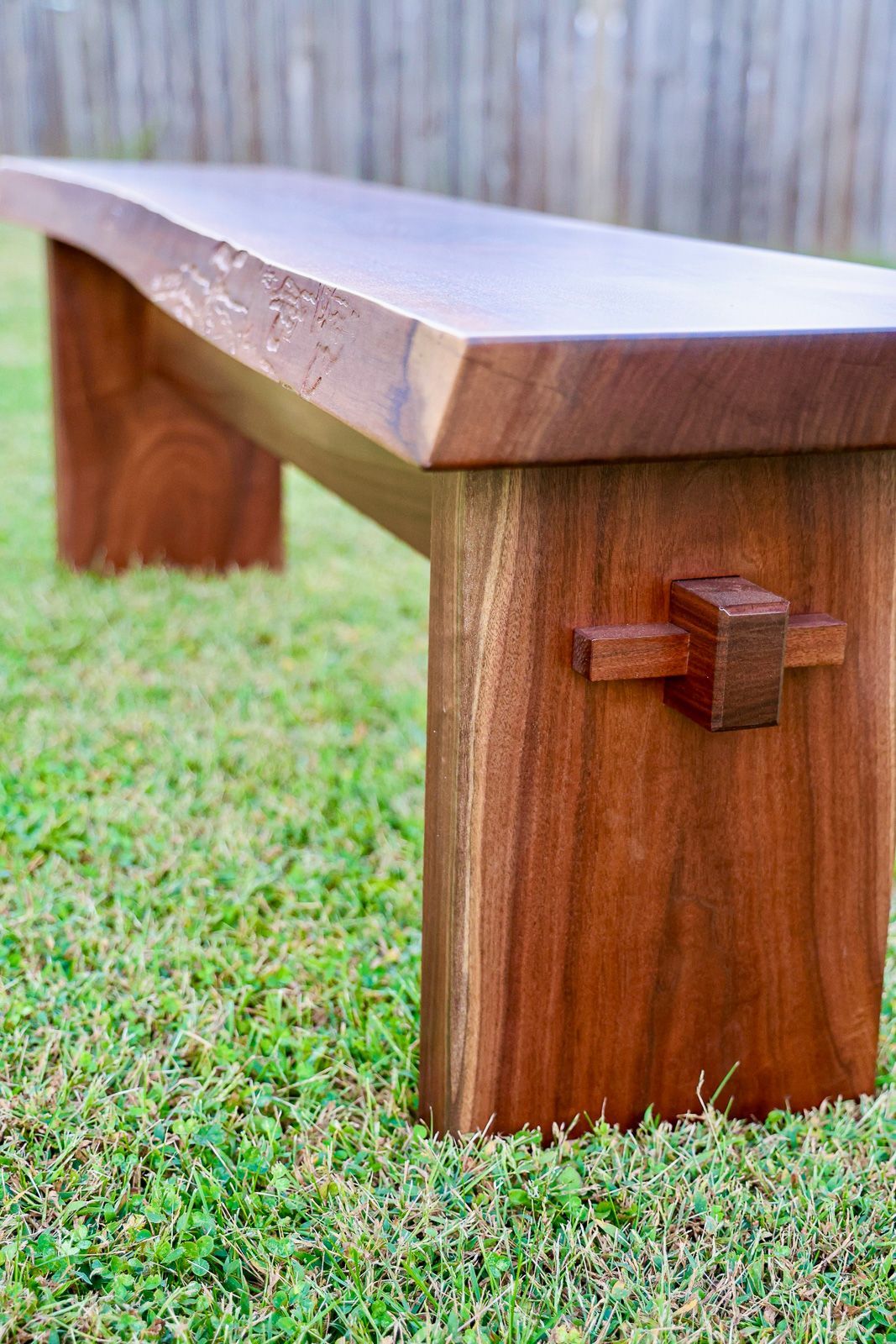 Black walnut bench with a live edge and an exposed wedged through-tenon joint at the leg. St. Charles, Iowa.