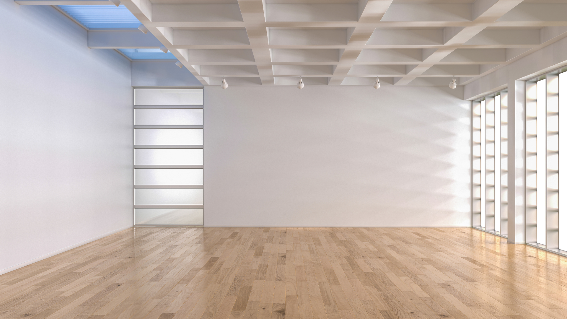 Empty modern room with wood floors, white walls, and large windows letting in bright light