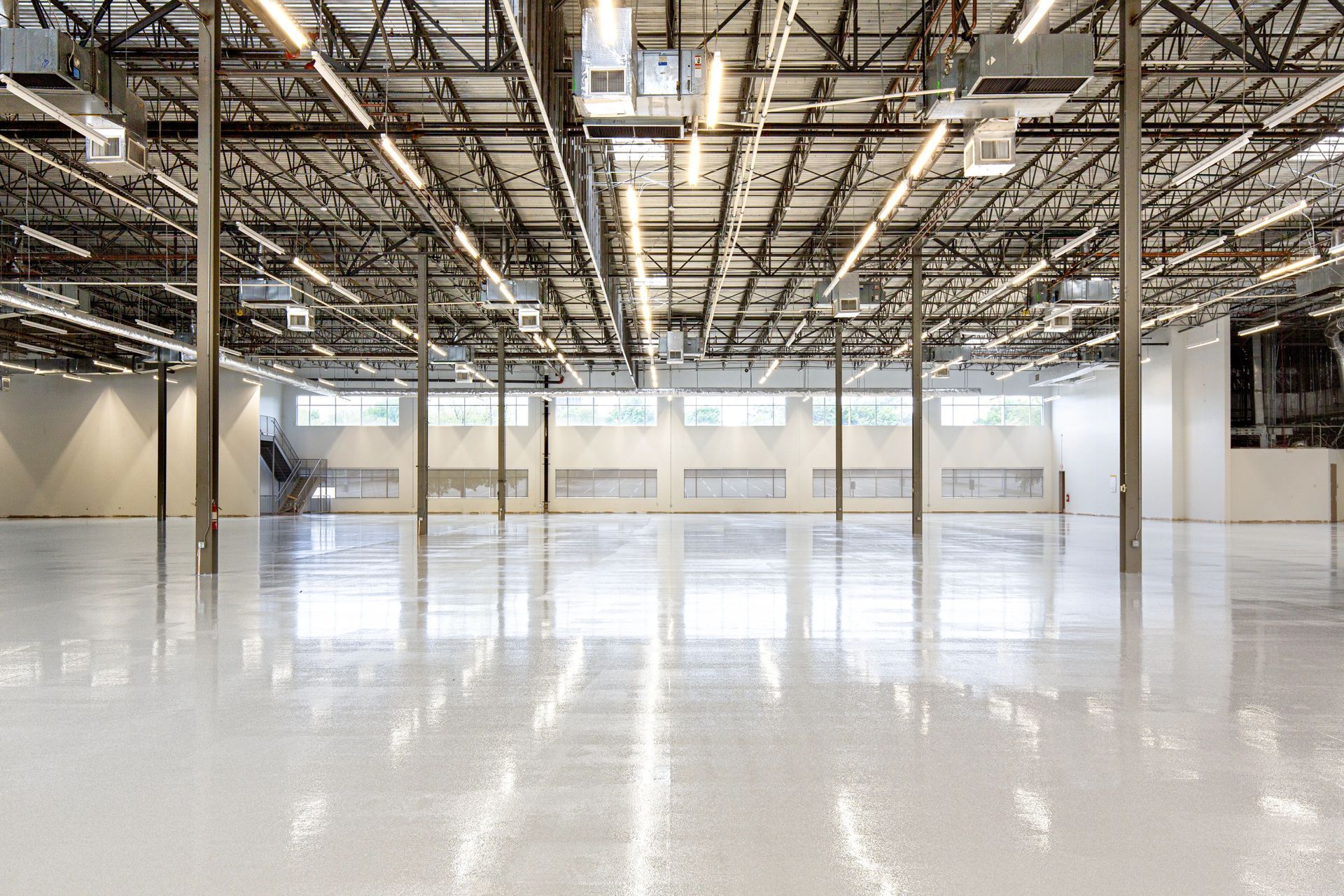 Empty industrial warehouse with polished white floor and exposed ceiling beams