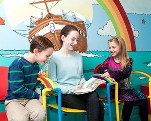 Parent completing patient forms at a pediatrician while boy and girl watch
