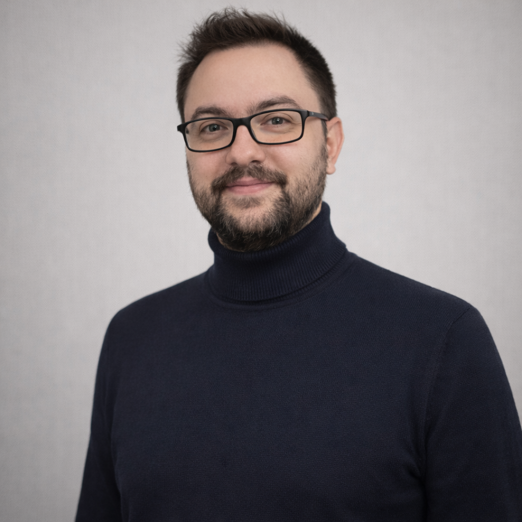 Un uomo in giacca e occhiali è in piedi in un ufficio.