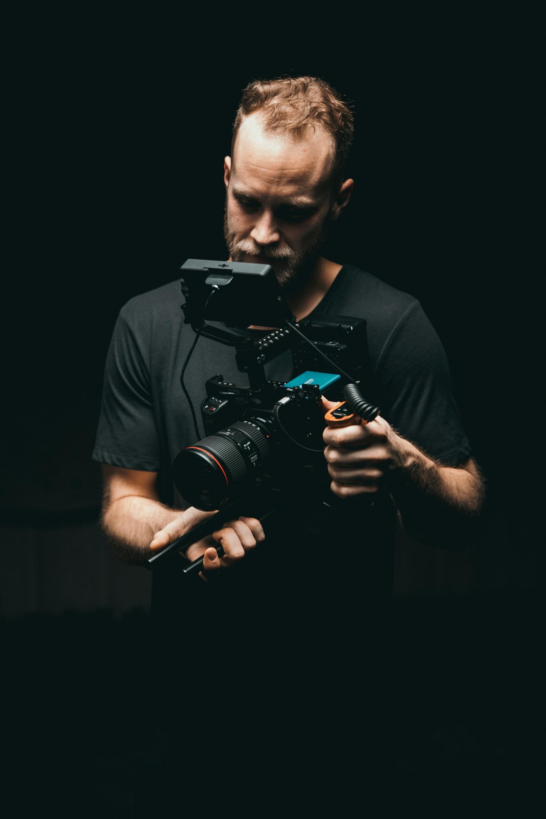 Un uomo tiene in mano una macchina fotografica in una stanza buia.