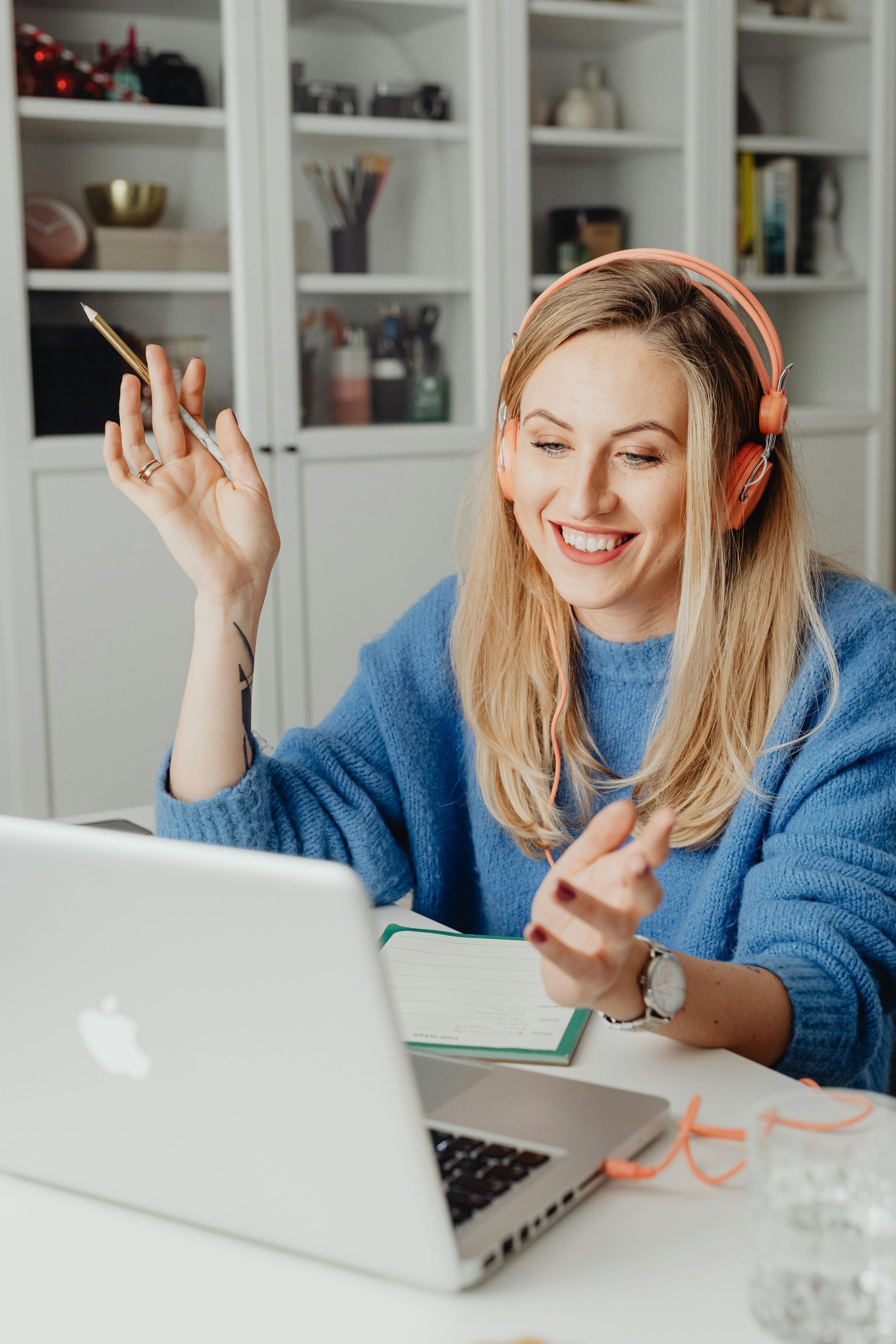 Una donna con le cuffie sorride durante una videochiamata su un computer portatile, in una stanza luminosa.