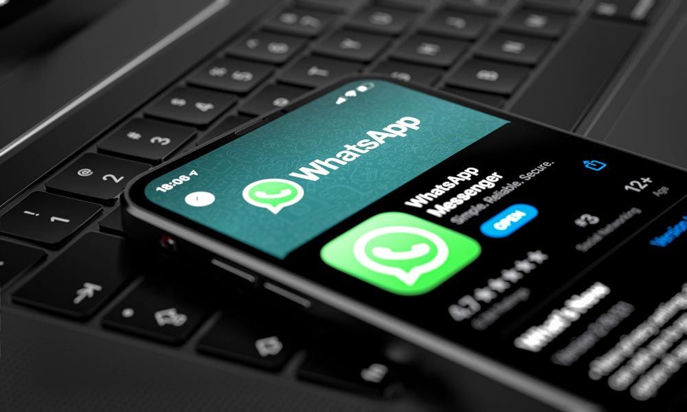 Smartphone displaying WhatsApp app on a laptop keyboard.