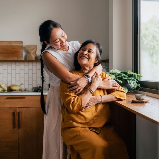 A young woman is hugging an older woman in a kitchen.