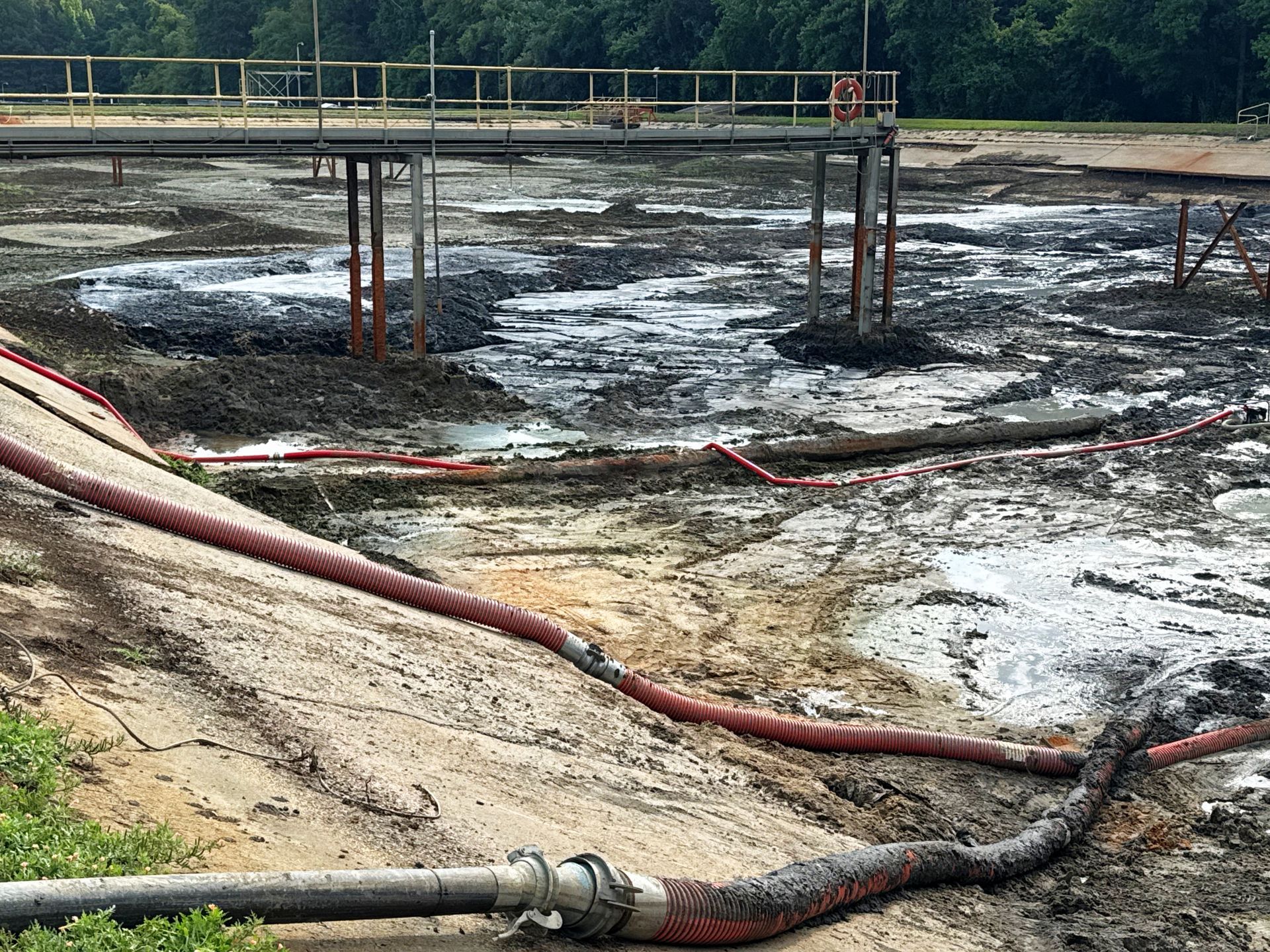 Suction and discharge hoses dewatering an aeration basin with catwalks still standing during North Carolina lagoon cleanout