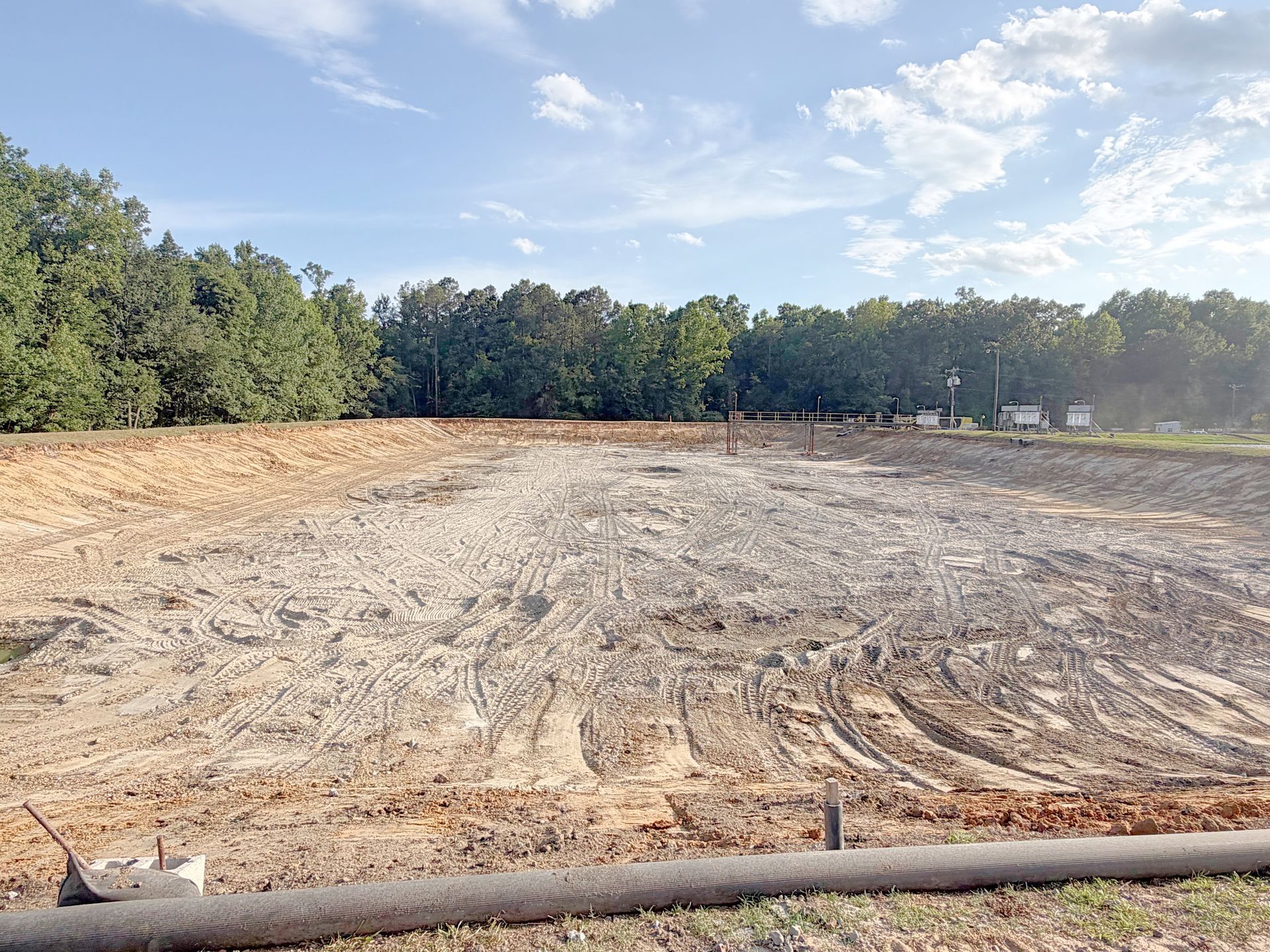 Fully cleared and regraded aeration basin with treatment plant infrastructure in the background after lagoon cleanout in North Carolina
