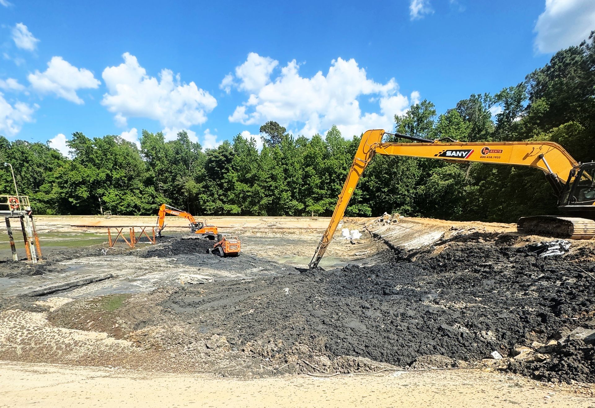 Long-reach excavator and tracked excavator working solidified sludge wall during aeration basin cleanout in North Carolina
