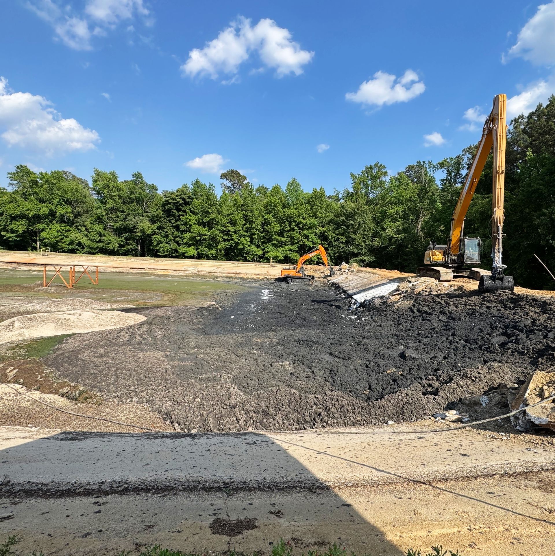 Excavators working alongside piles of solidified sludge during aeration basin cleanout in eastern North Carolina