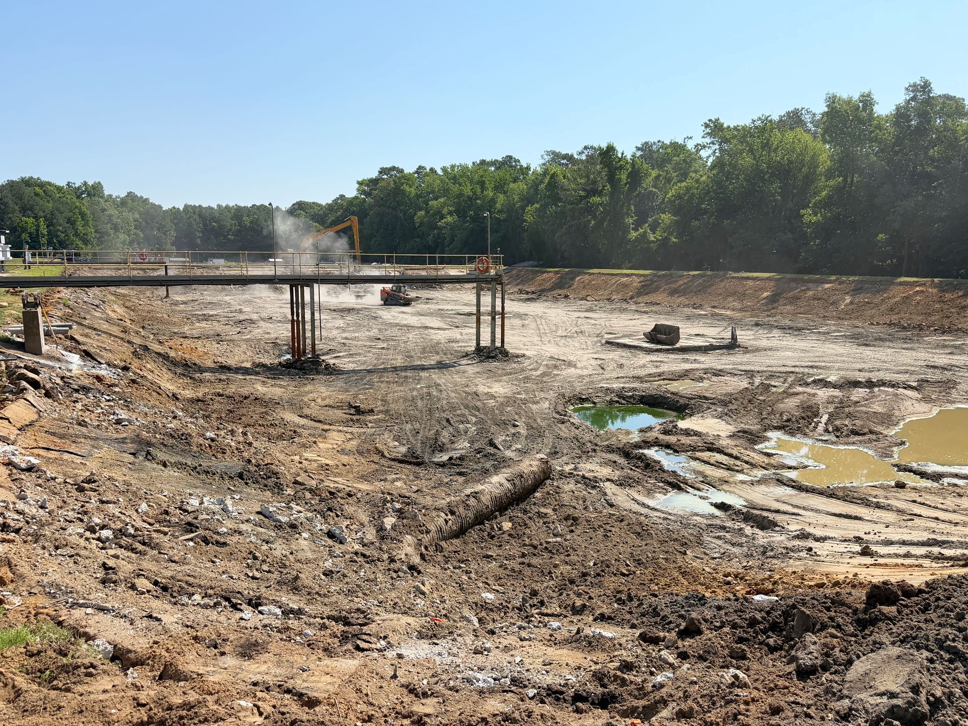 Basin nearly cleared to clean bottom with catwalk still standing during late-stage lagoon cleanout at a North Carolina wastewater facility