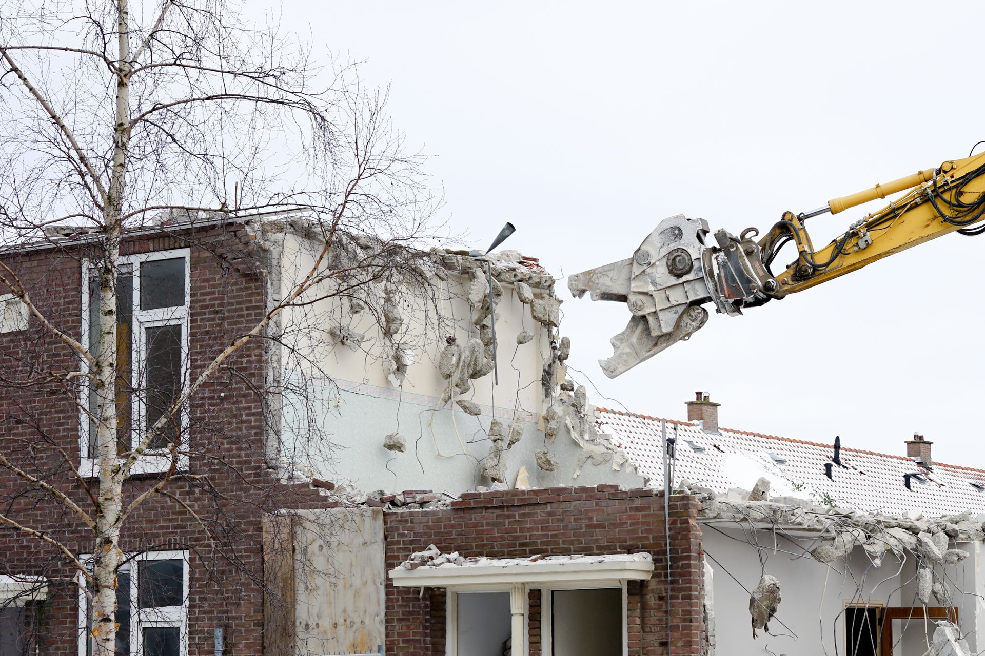 Excavator removing contaminated soil and legacy materials from a demolition site during environmental remediation