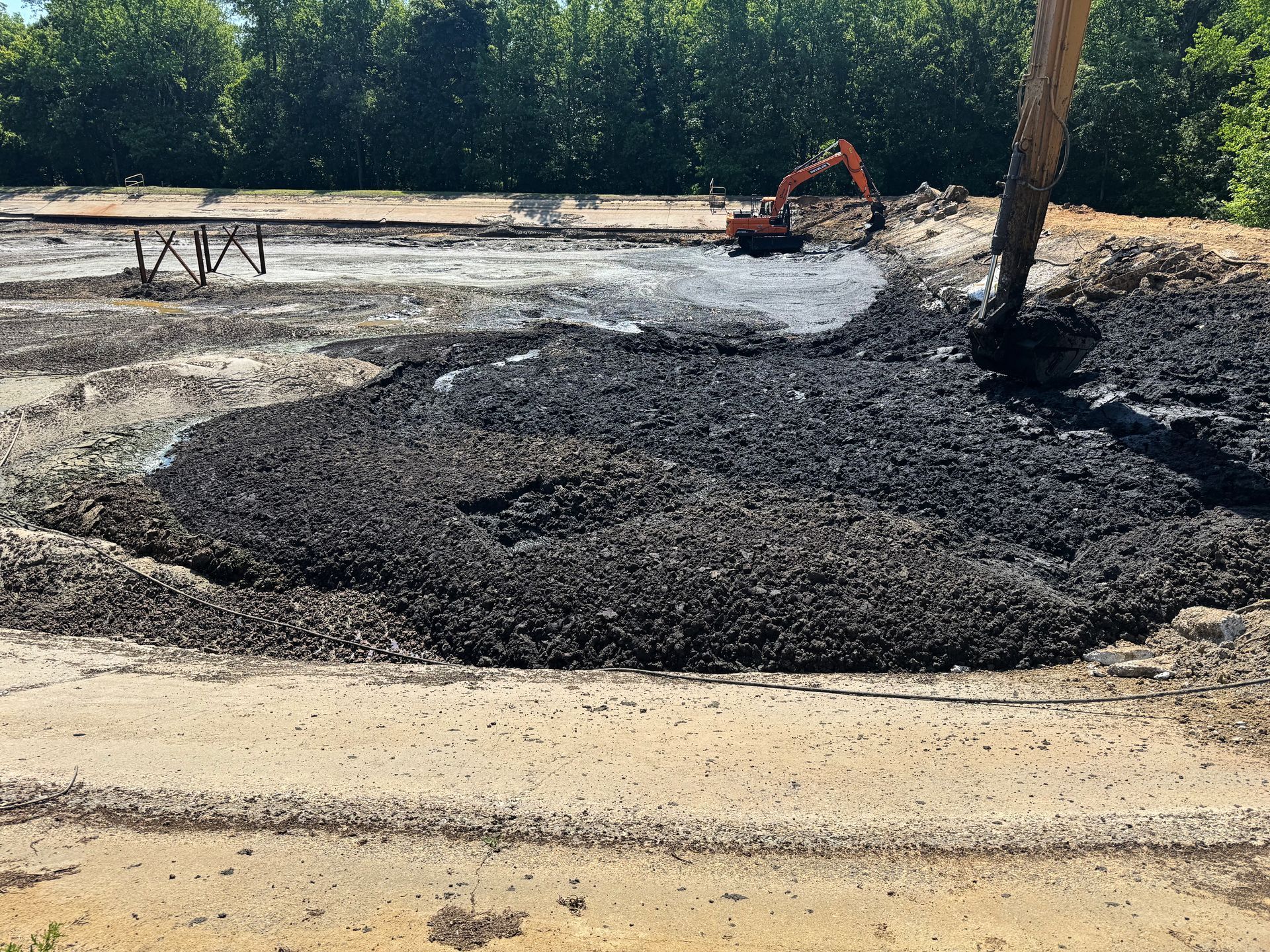 Excavators working a large sludge mound from the clean perimeter during solidification and removal at a North Carolina aeration basin