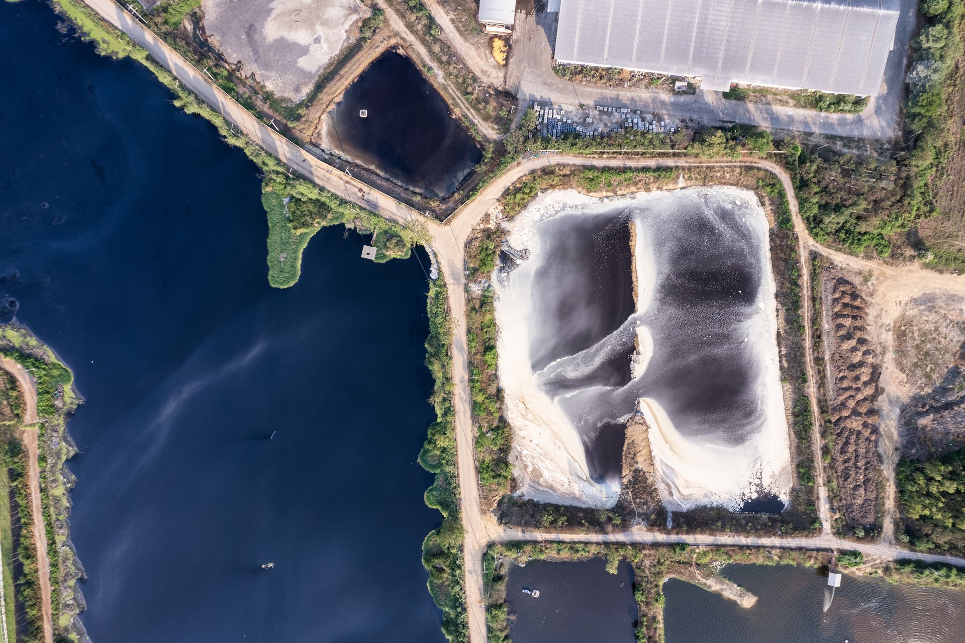 Aerial view of industrial wastewater lagoons during cleanout operations at a power generation facility