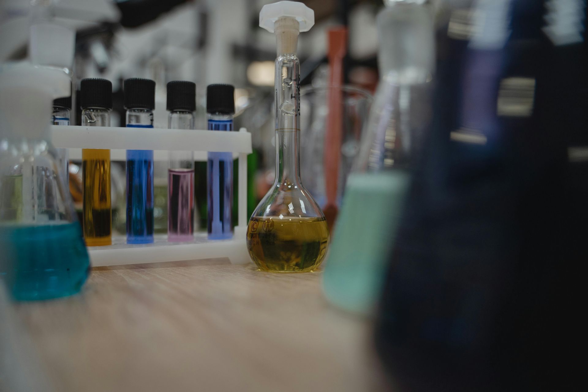 Lab bench with glass bottles and a flask of colored liquids in a blurred laboratory setting