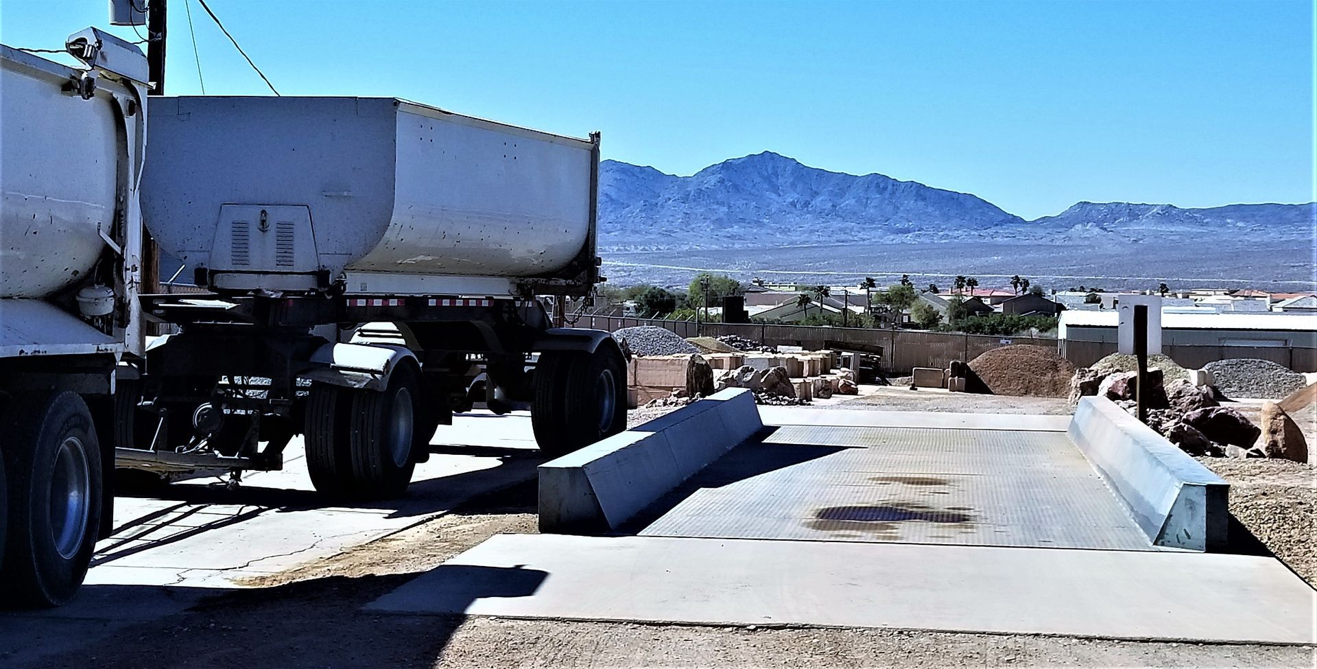 Trucks at a roadside checkpoint with mountains in the background under a clear blue sky