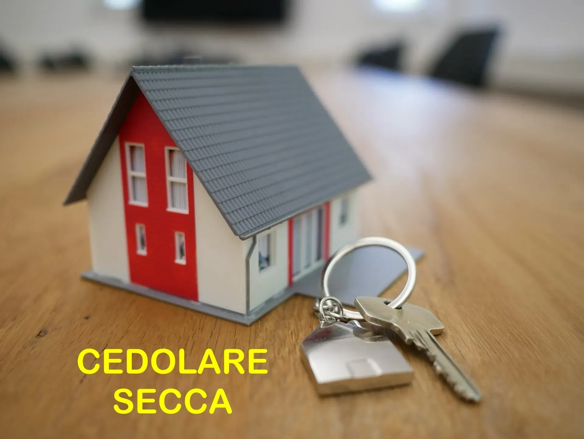 un modellino di casa e chiavi su un tavolo con la scritta cedolare secca sul fondo