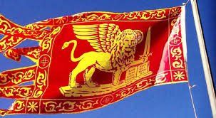 Una bandiera rossa e oro con sopra un leone sventola nel vento.