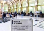 Un cartello è seduto di fronte a una folla di persone in un edificio.