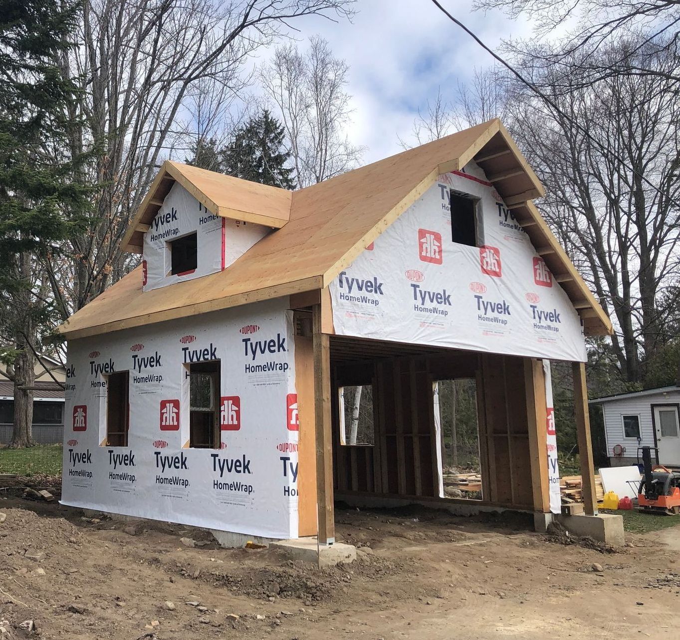 Construction of a detached garage with an open garage bay, covered in Tyvek wrap.