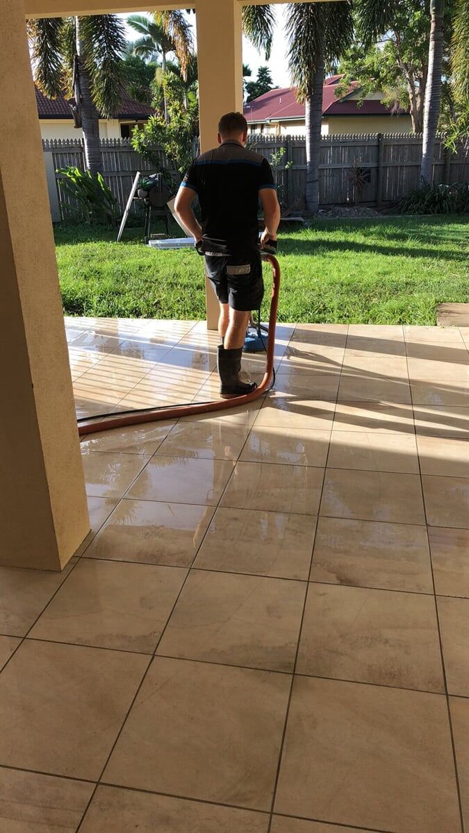 Person Pressure Washing a Tiled Patio — Professional Cleaners In Yeppoon in Yeppoon, Qld