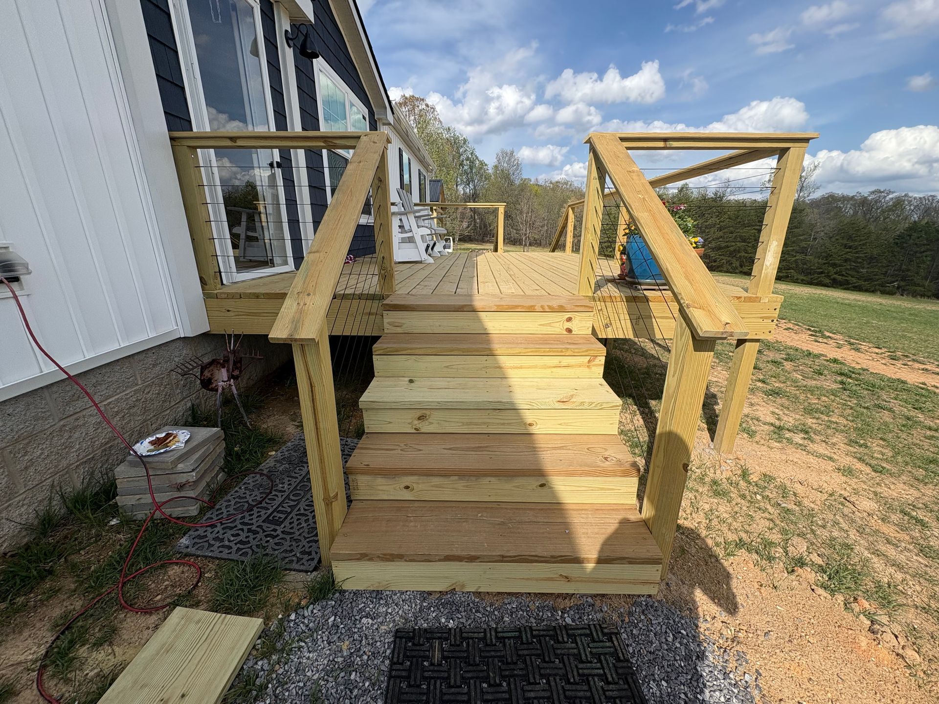 Wooden outdoor staircase and deck attached to a house with handrails.