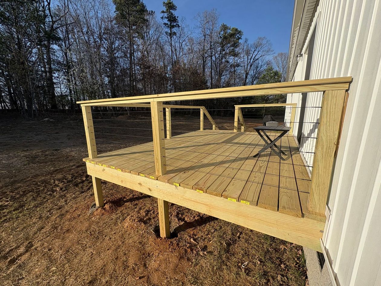 Wooden deck under construction attached to a house on a sunny hillside