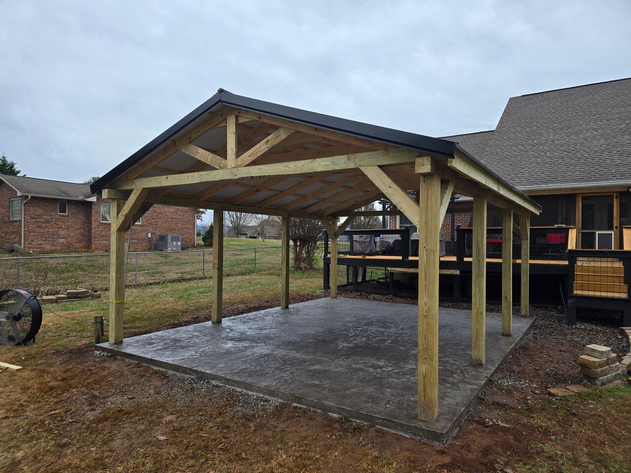 A wooden pavilion is sitting in the backyard of a house.