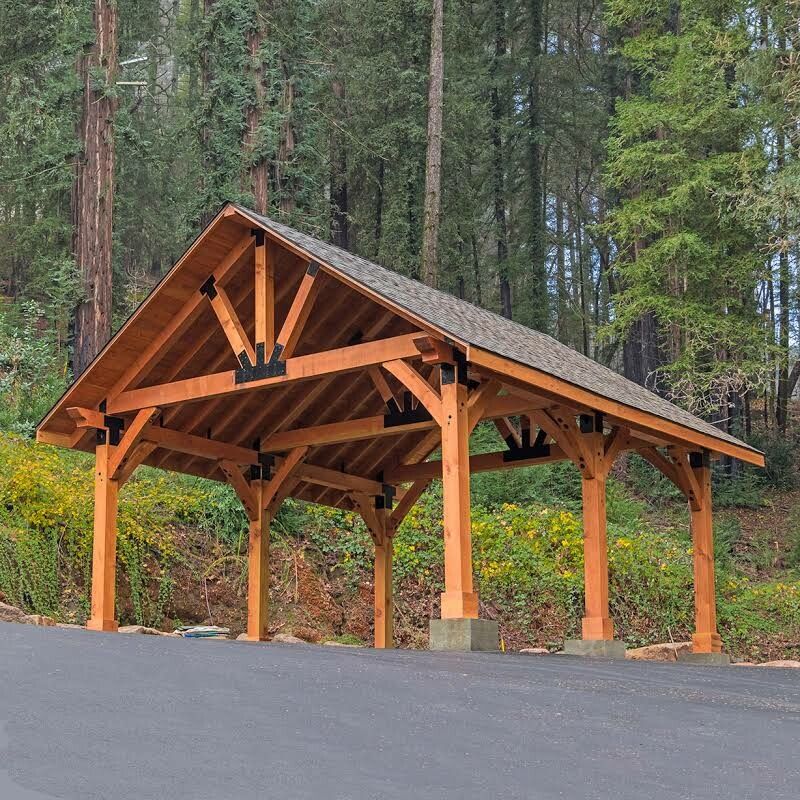 A wooden pavilion is sitting on the side of a road in the woods