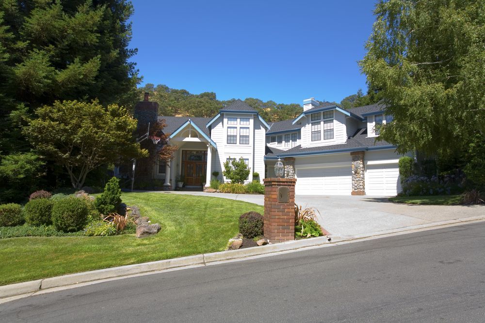 A large white house sits with concrete driveway.