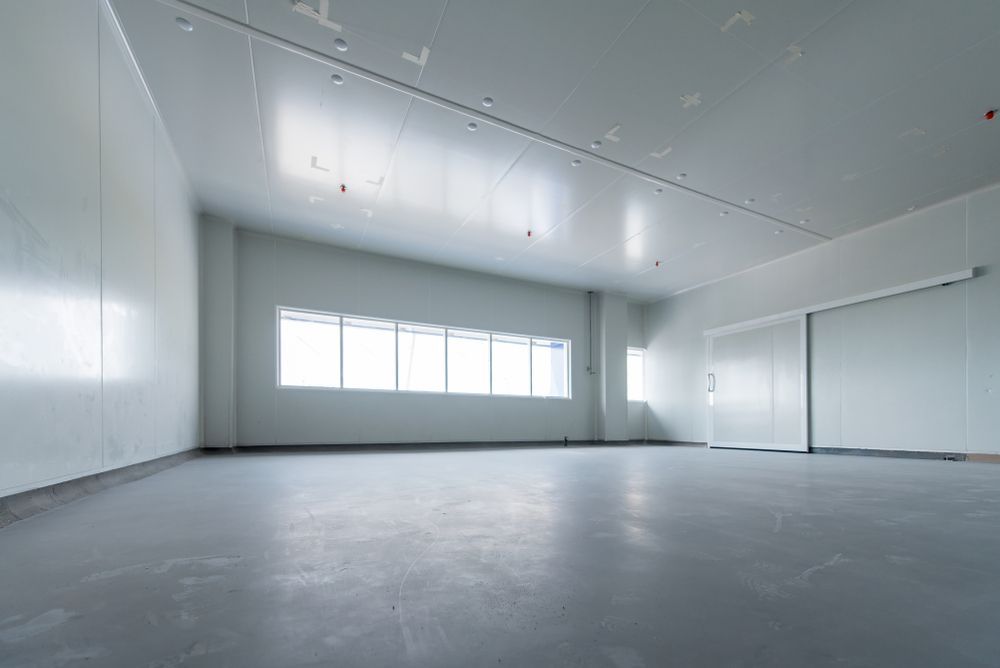 Empty, sterile, white room with gray floor and a large window.  A sliding door is visible.