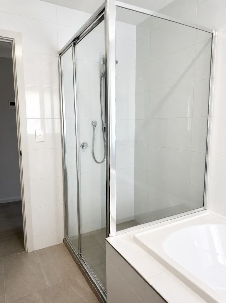 Modern bathroom with glass-enclosed shower next to a white bathtub sink area