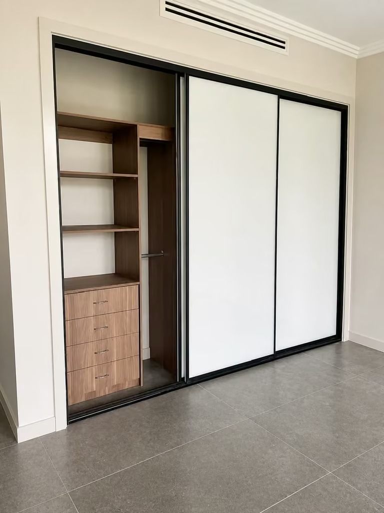 Open closet with shelves and drawers, featuring white sliding doors and a dark frame in a tiled room.