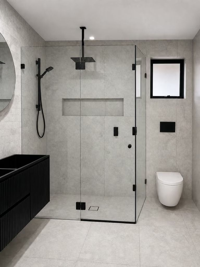 Modern gray bathroom with glass shower, black fixtures, toilet, and vanity.