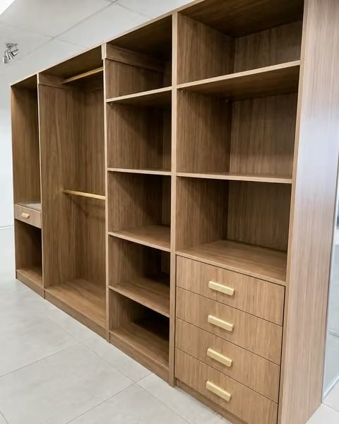 Wooden wall unit with open shelves, a hanging section, and a four-drawer cabinet in a room