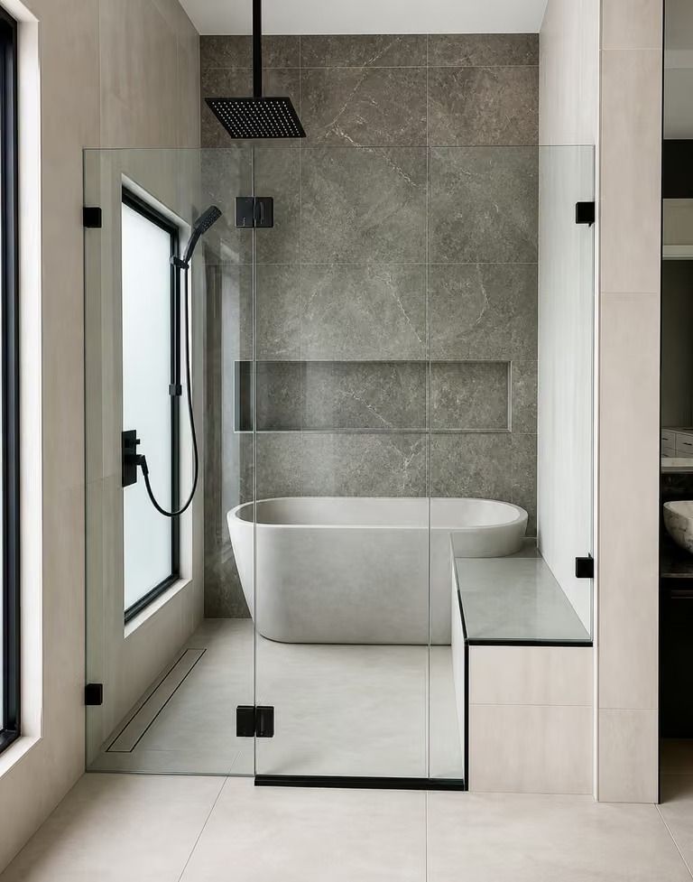 Modern bathroom with a frameless shower, freestanding tub, and neutral stone tile finishes