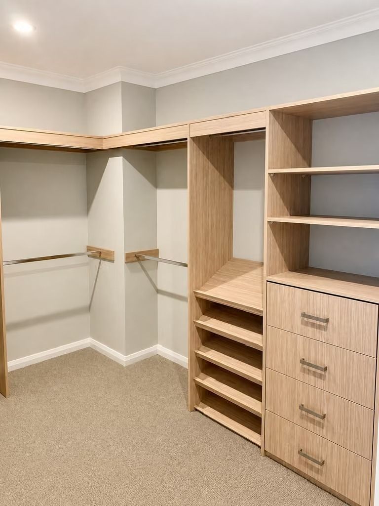 Built-in walk-in closet with shelves, drawers, hanging rods, and beige carpet.