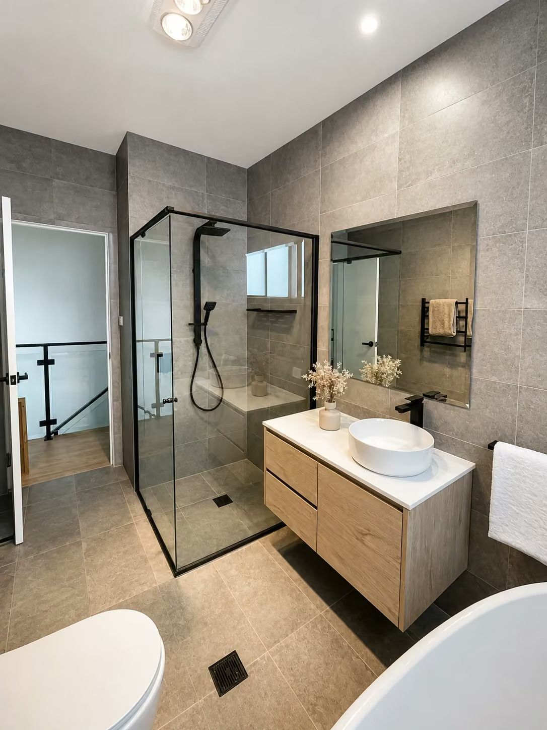 Modern gray bathroom with glass shower, floating wood vanity, and large mirror