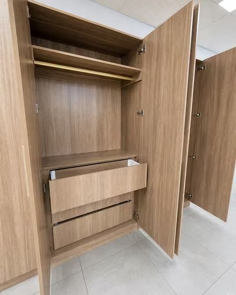 Open wooden wardrobe with shelves and a pull-out drawer in a showroom or closet display.