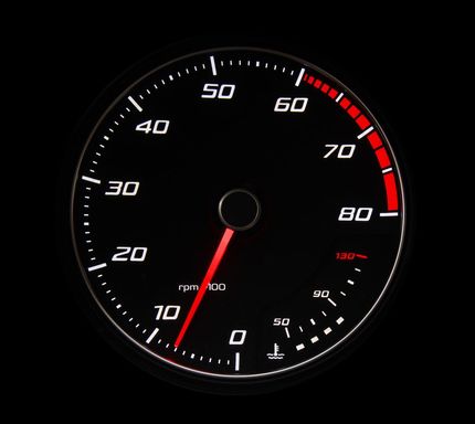 Close-up of a black tachometer gauge with white numbers and a redline zone on the right.