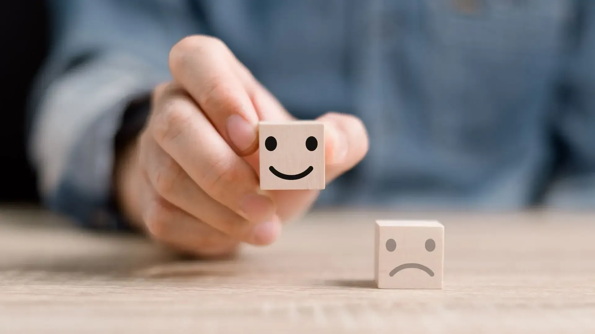 A person is holding a wooden block with a smiley face on it.