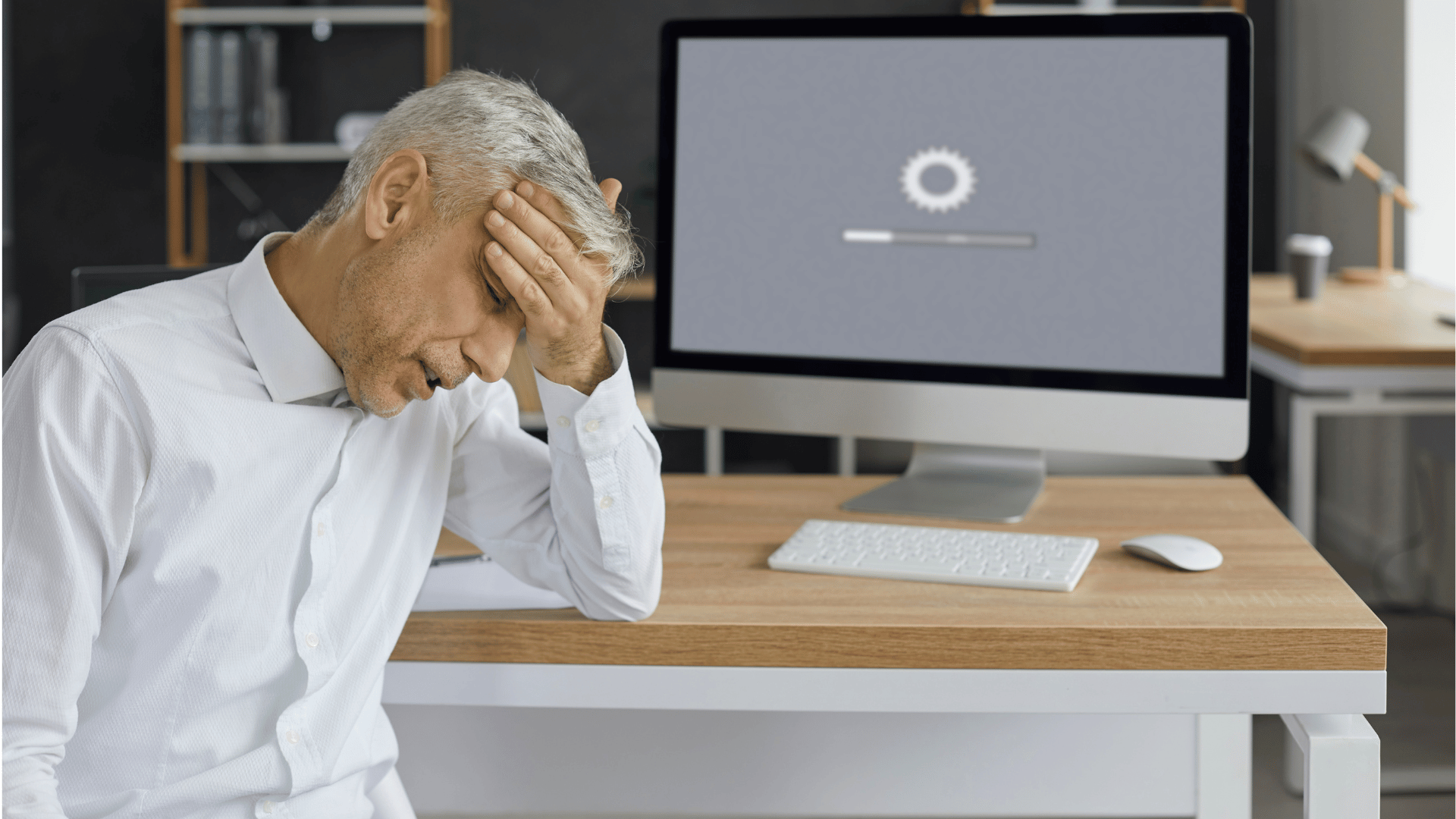 a man is sitting at a desk with his head in his hands in front of a computer .