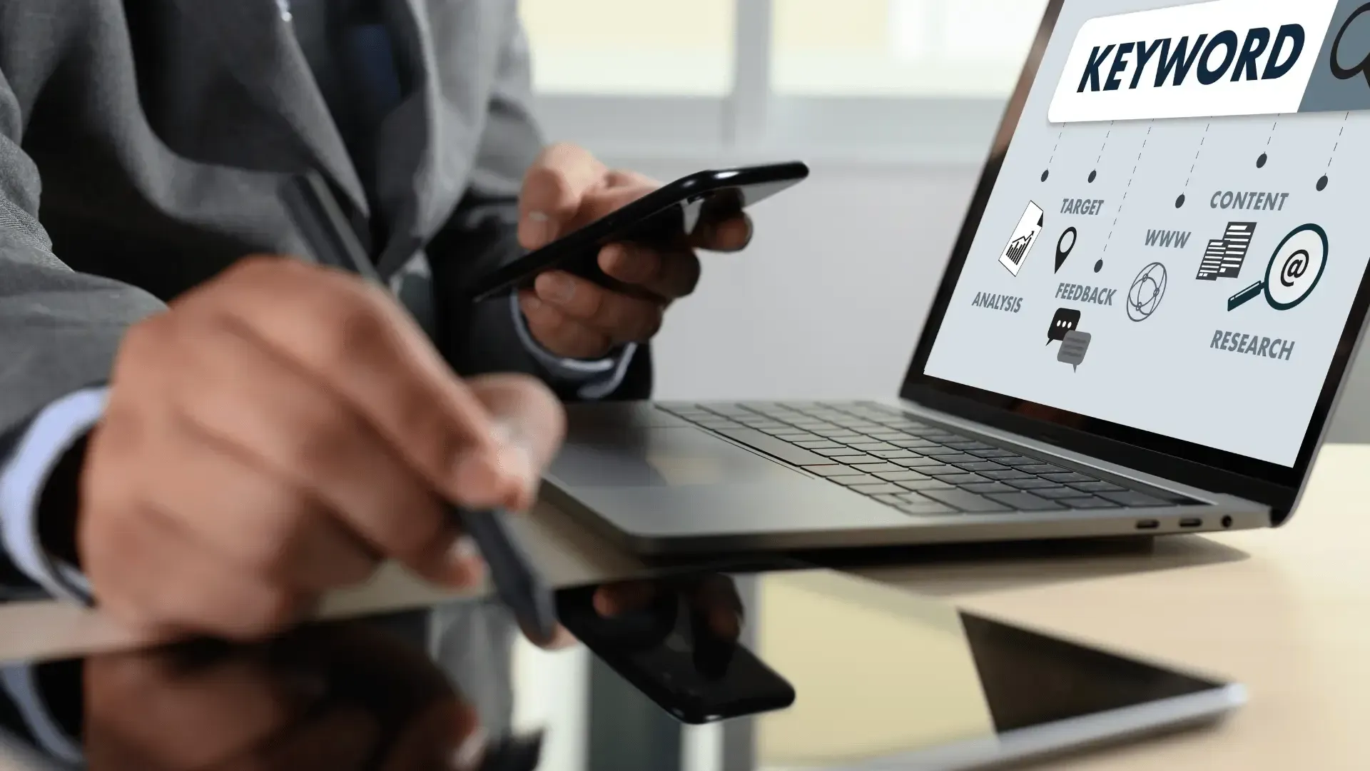 A man is using a laptop computer while holding a cell phone.