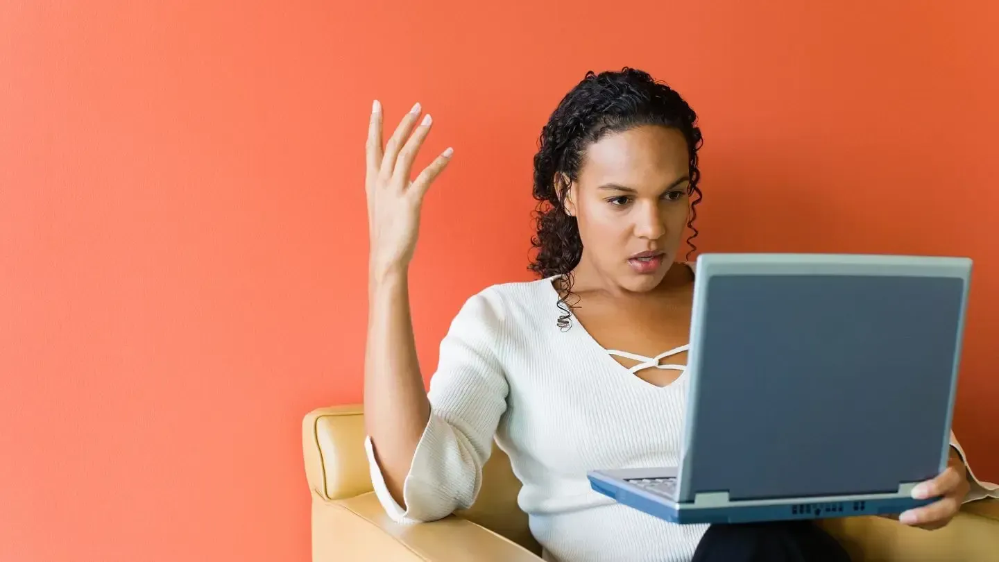 A woman is sitting in a chair using a laptop computer