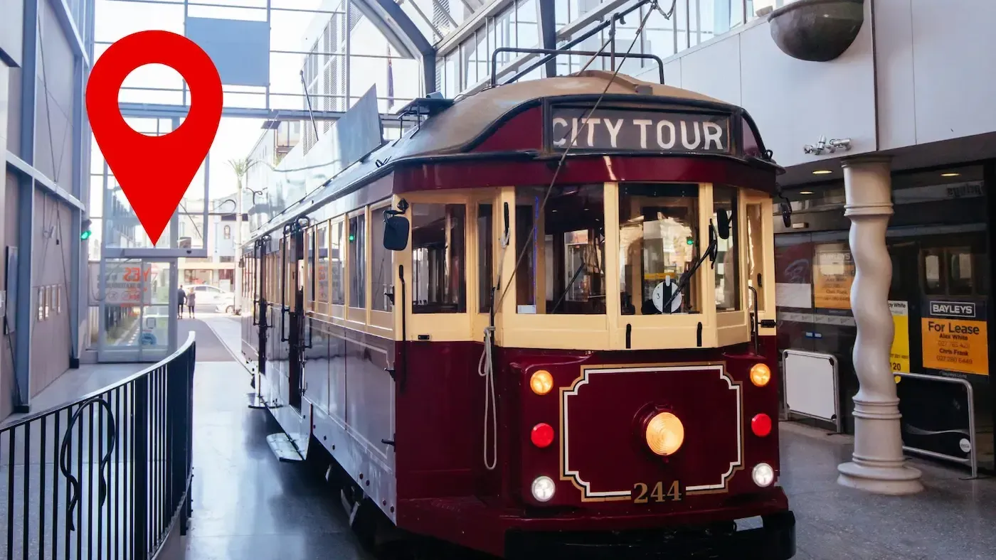 A city tour trolley is parked in front of a building.